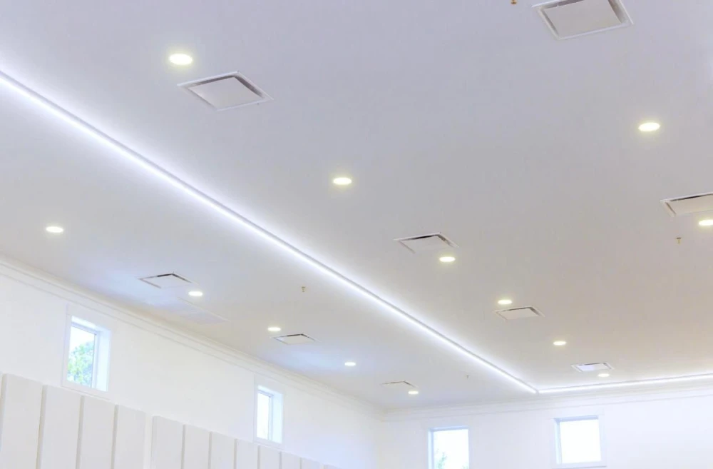 Freshly installed recessed lighting and LED cove lighting on a bright white ceiling