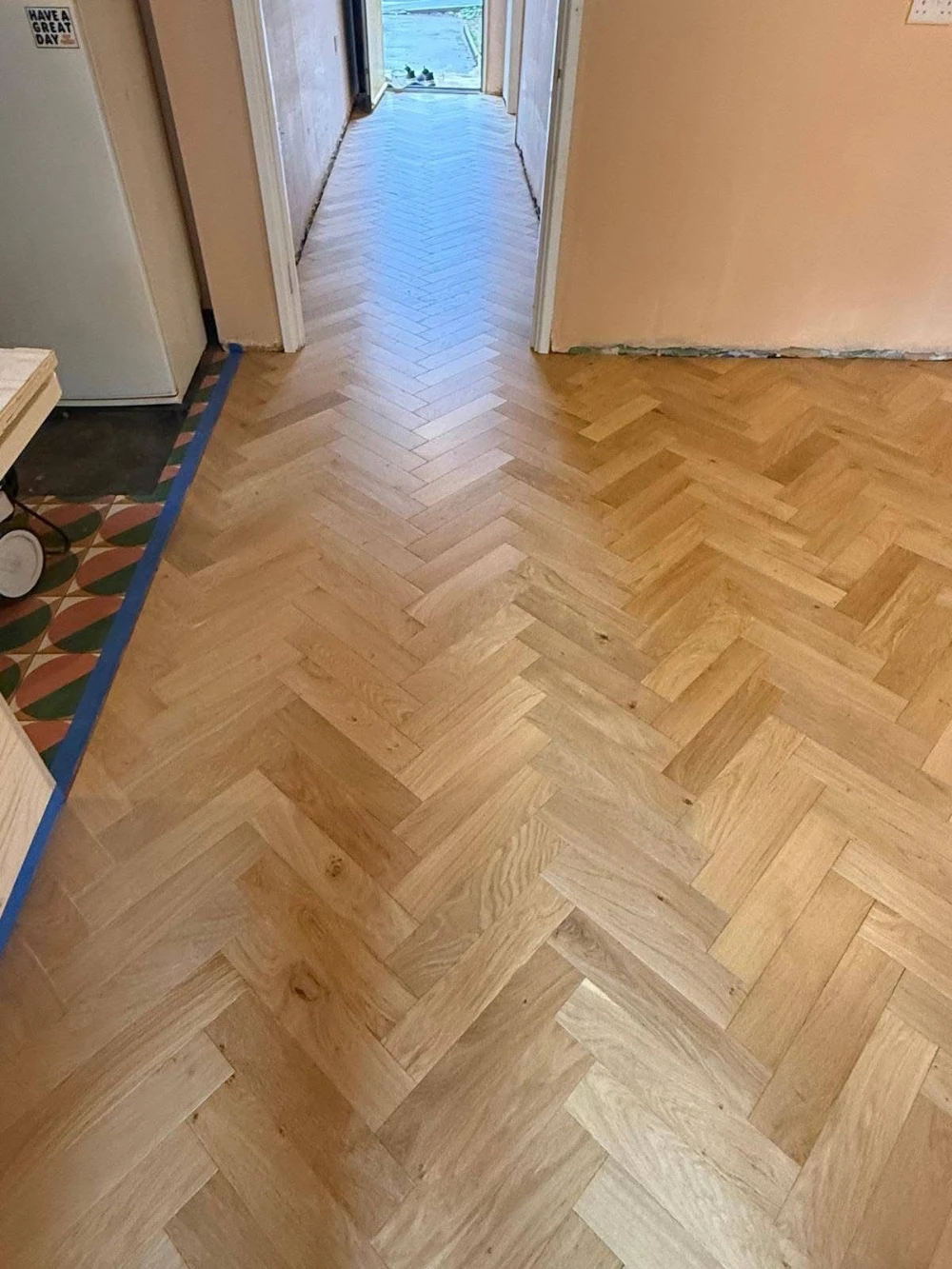 Completed white-oak herringbone floor running down a hallway