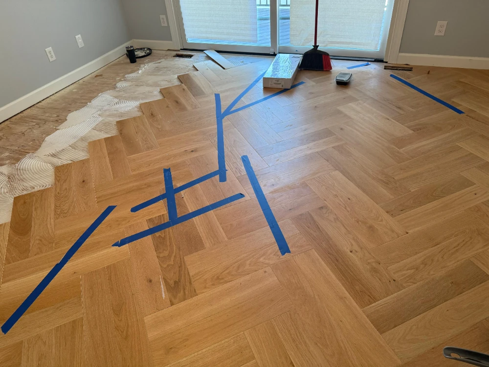 Herringbone hardwood installation in progress with layout lines taped out