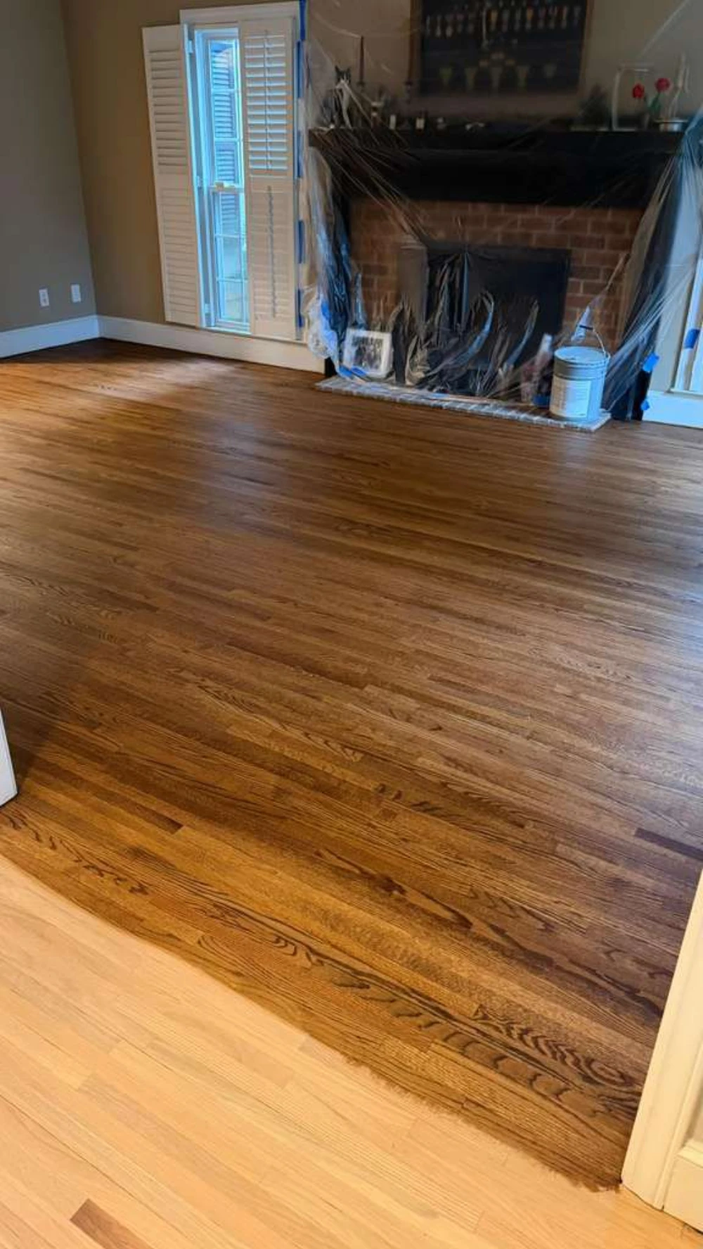 Red oak hardwood floor refinished with a rich dark stain by a brick fireplace