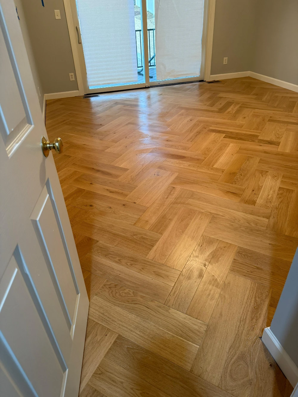 Herringbone hardwood floor with crisp white trim and door