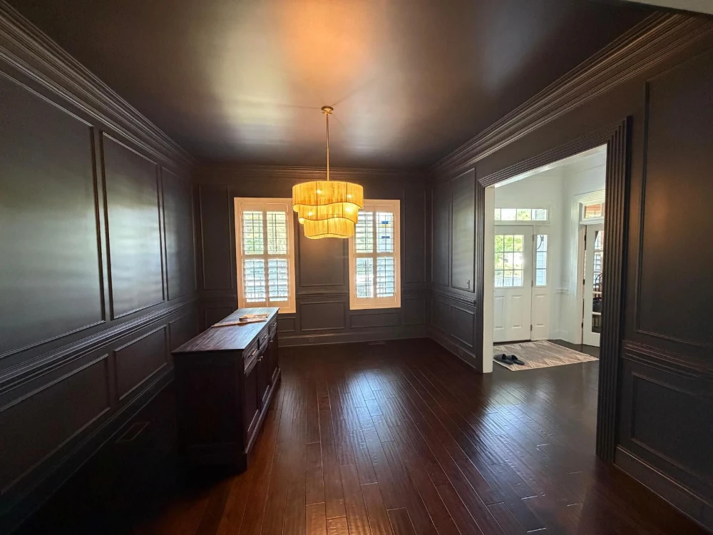 Formal room with dramatic dark painted wainscoting and a gold chandelier