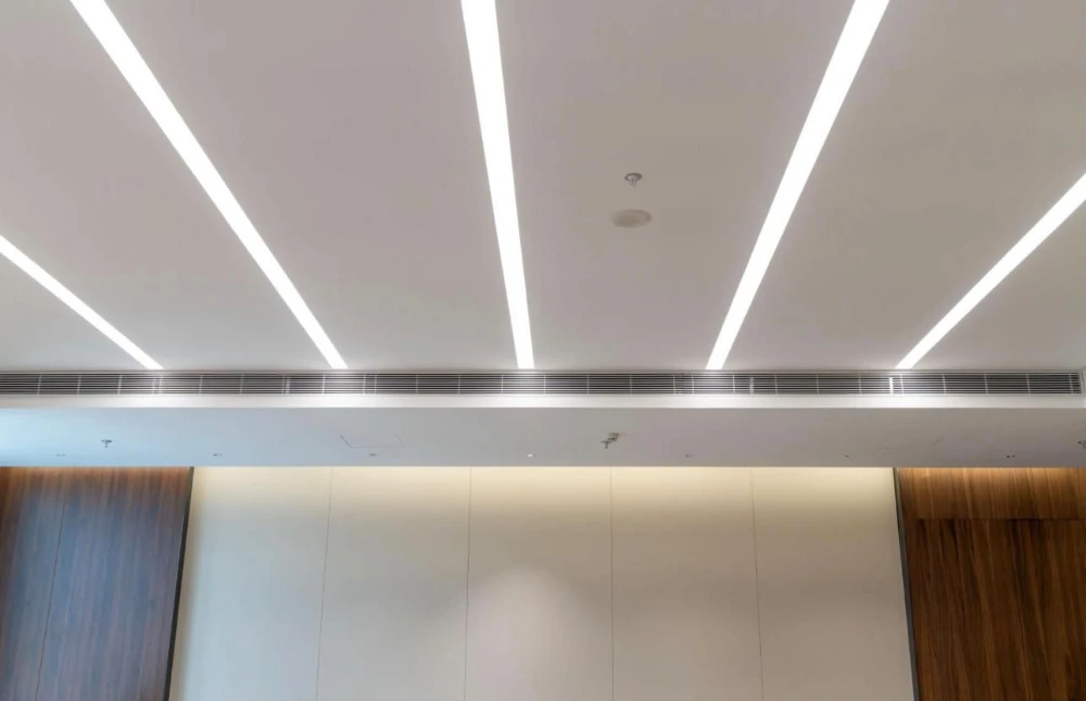 Linear LED ceiling lighting with wood-panel walls in a modern interior