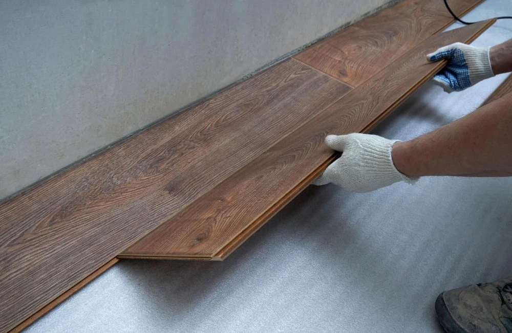 Installer laying luxury vinyl plank flooring over a prepared subfloor