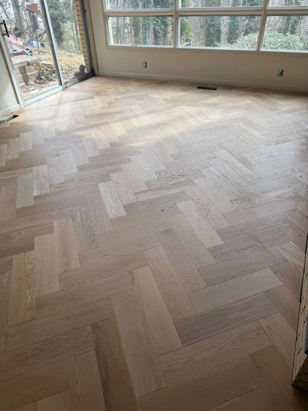 Newly finished white-oak herringbone hardwood floor in a sunlit room
